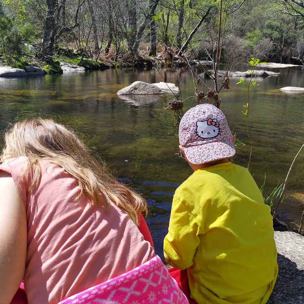 Niños jugando junto al río en un paisaje serrano lleno de vida.