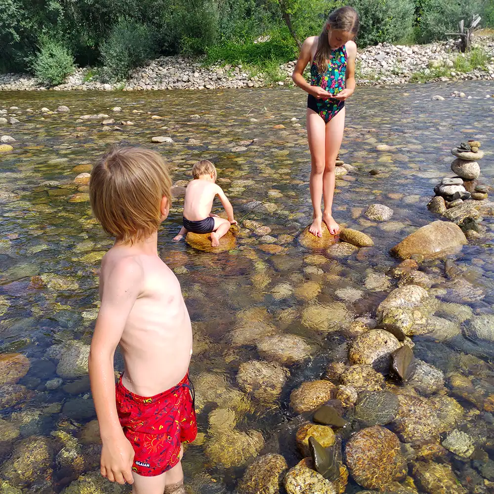 Niños retozan en un arroyo de montaña, verano y diversión en la Serra da Estrela.