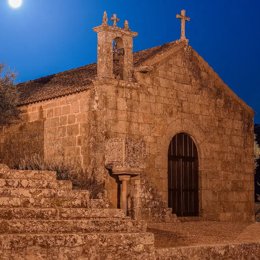 Capilla de piedra iluminada por luz artificial y lunar en la Serra da Estrela.