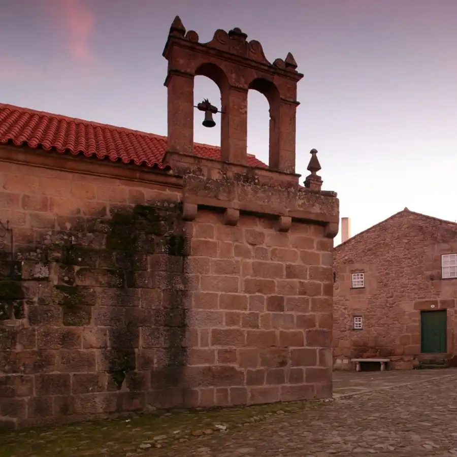 Campanario de piedra con campanas, evocando la historia de la Serra da Estrela.