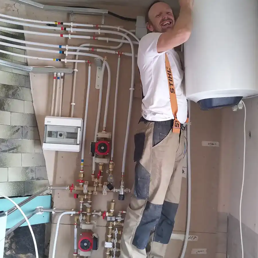 Un técnico inspecciona y repara instalaciones de fontanería en un espacio rústico.