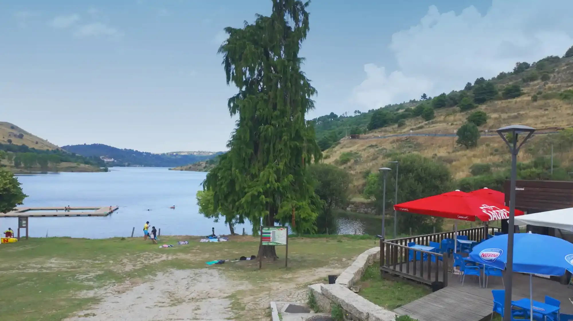 Family swimming at a river beach surrounded by trees in Serra da Estrela.