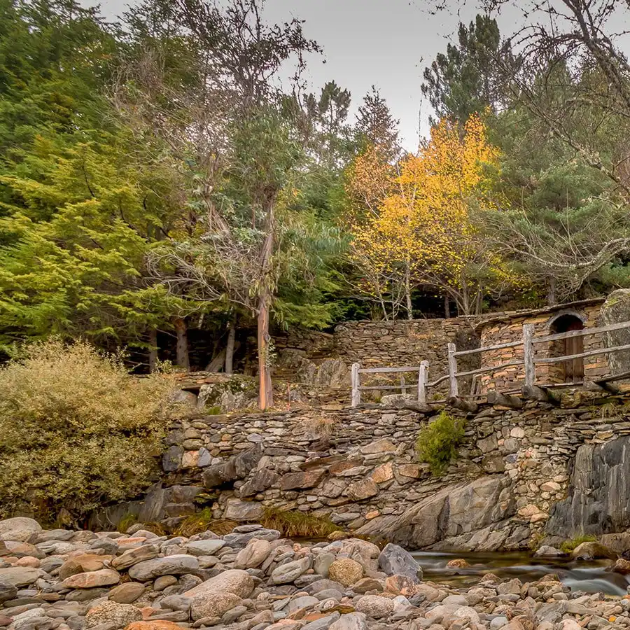 Ouderwetse stenen brug in de Serra da Estrela, omgeven door herfstkleuren.
