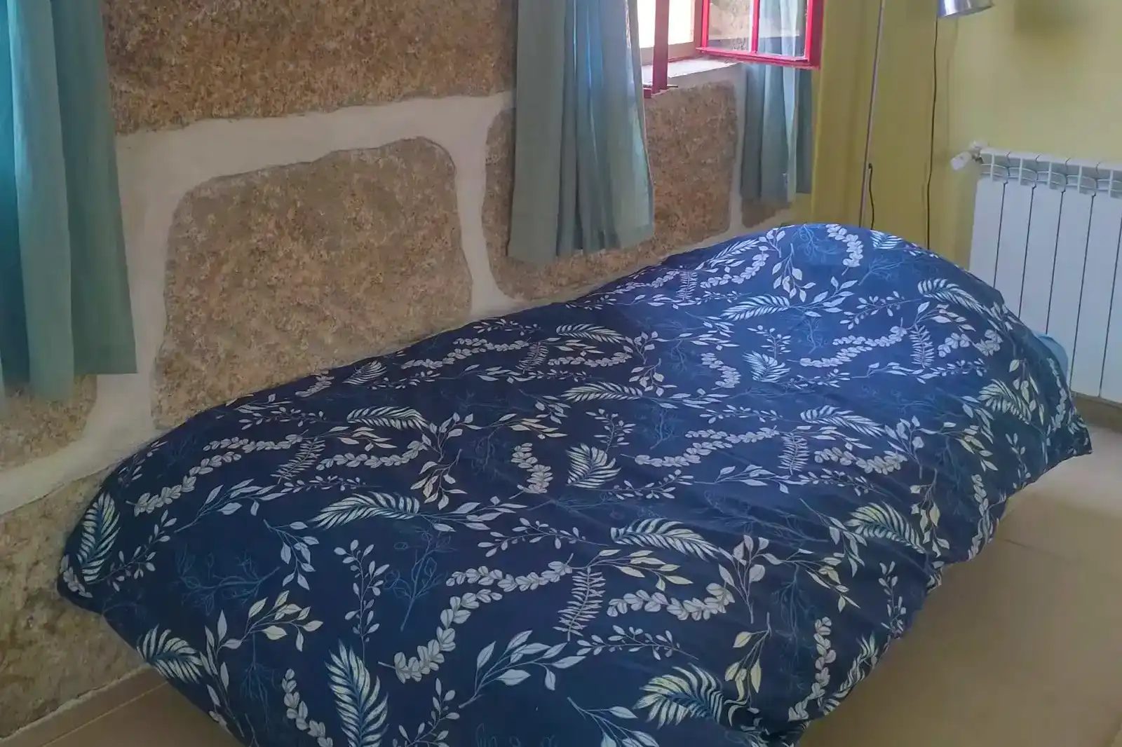 Een knus bed in de Serra da Estrela: rust en natuur dichtbij. Een knus bed met bloemenprint in een rustieke kamer met uitzicht.