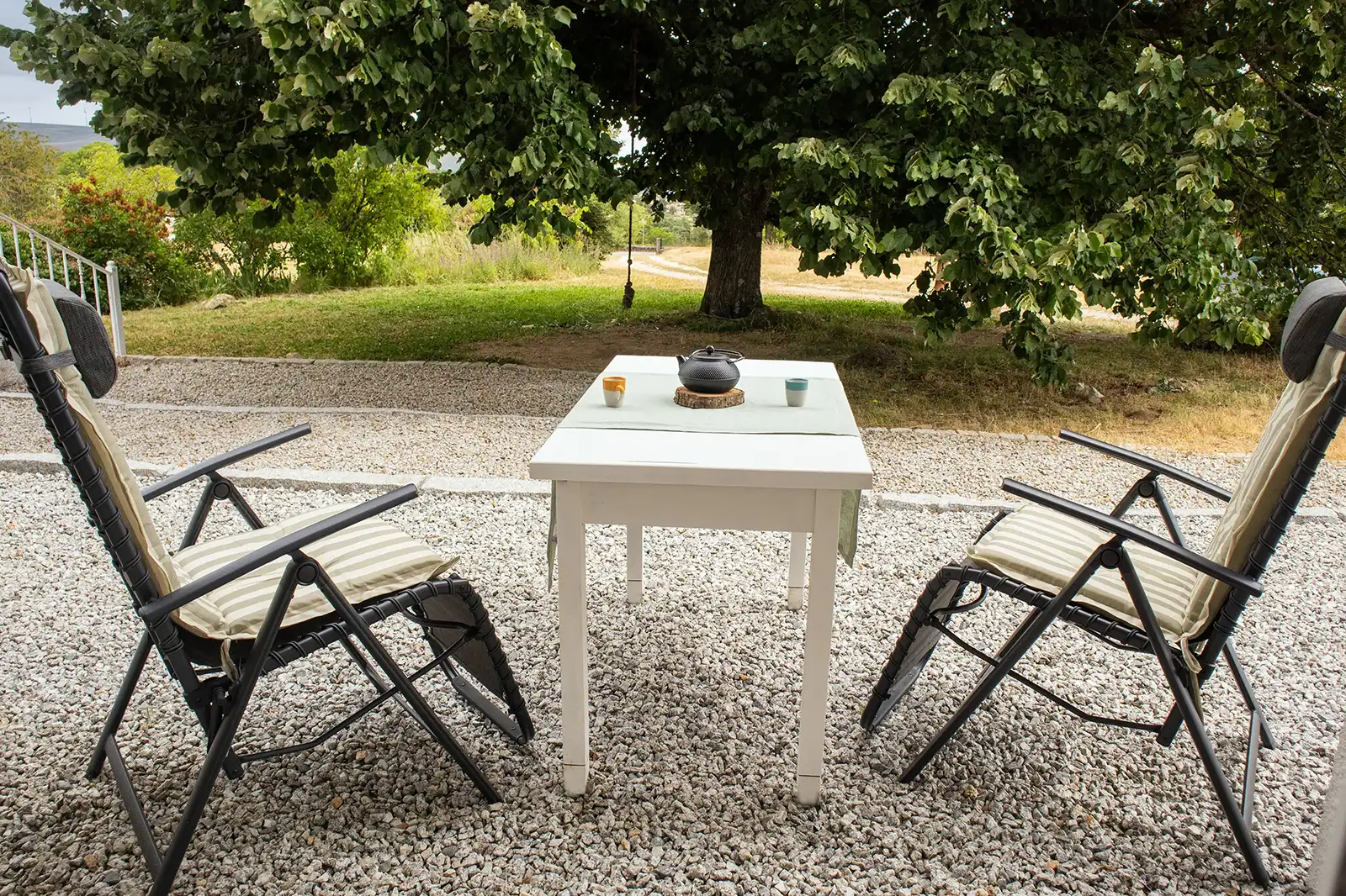 Refúgio de paz: momentos serenos na Serra da Estrela. Refúgio sereno: cadeiras confortáveis e mesa rústica num jardim montanhoso.