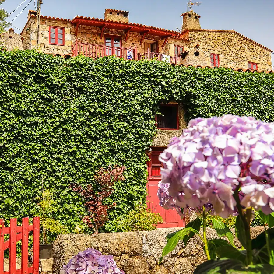 Casa de xisto charmosa na Serra da Estrela, rodeada de flores e tranquilidade.
