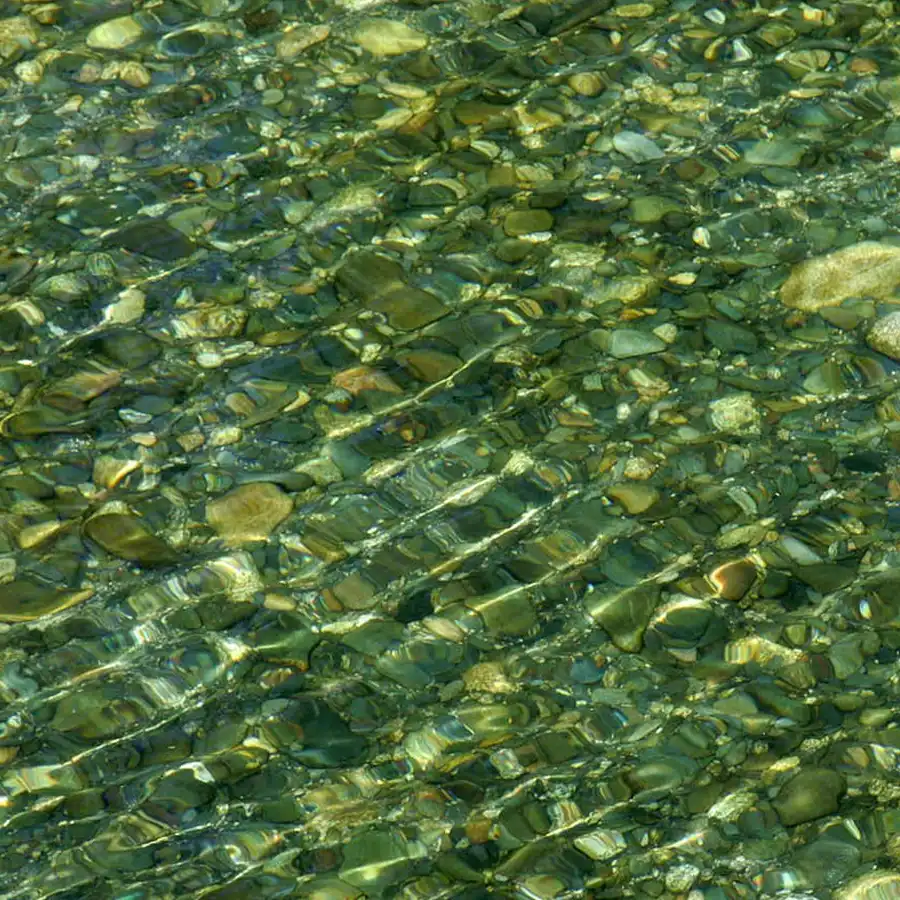 Leito de rio pedregoso, águas límpidas e reflexos naturais na Serra da Estrela.