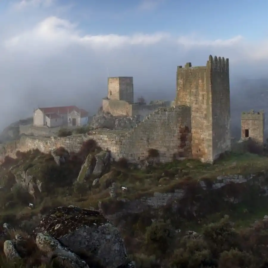 Castelo medieval envolto em névoa, testemunha de histórias e tempos passados.